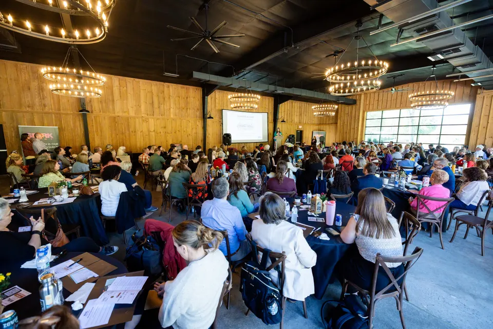 A wide view of the barn at Deerwoode Reserve, every round table filled beneath rows of chandeliers