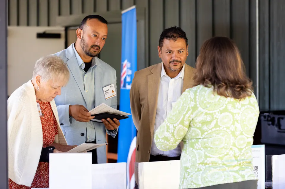 Four attendees read printed story cards together at a simulator station