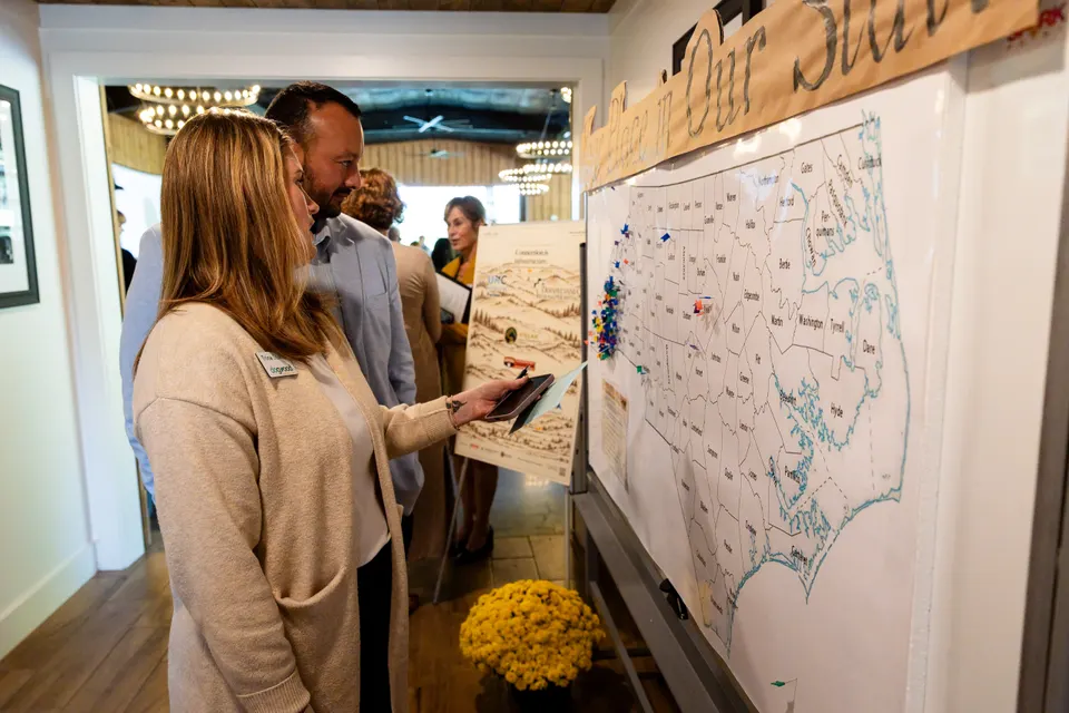 Attendees study a big map of North Carolina pinned with where everyone works
