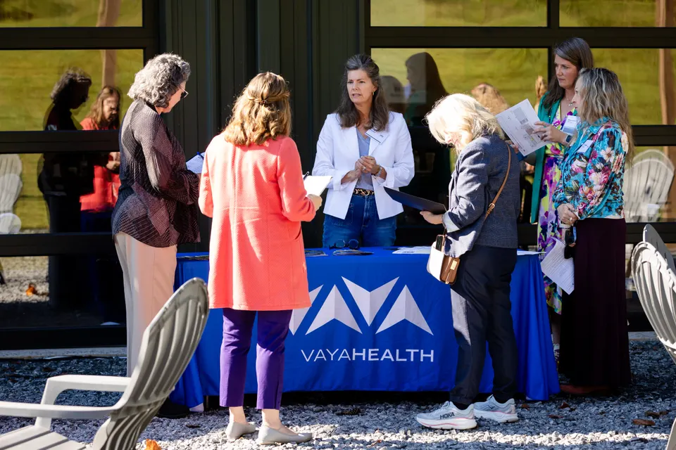 Attendees gather at a partner organization’s table under the pavilion