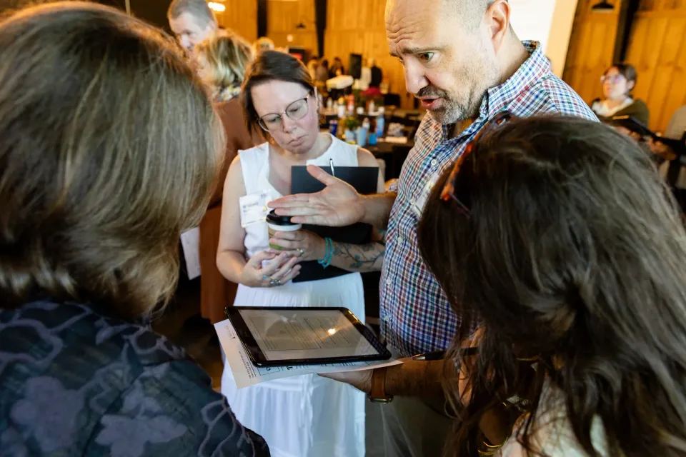 Attendees working through the Rural Health Field Simulator on a tablet.