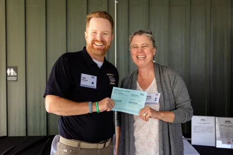 Two attendees laugh together as they hold up a Connection to Action card at the October 1 convening.