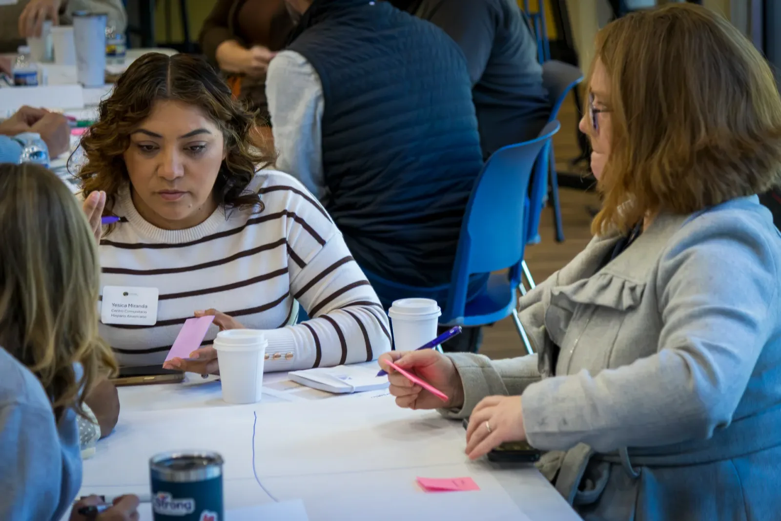 Attendees at a round table write on sticky notes during a small-group exercise at the Collaboration Lab.